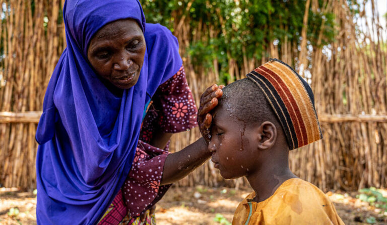 A mother in Nigeria washes the face of her son having accessed hygiene education on protecting her and her family from Neglected Tropical Diseases.